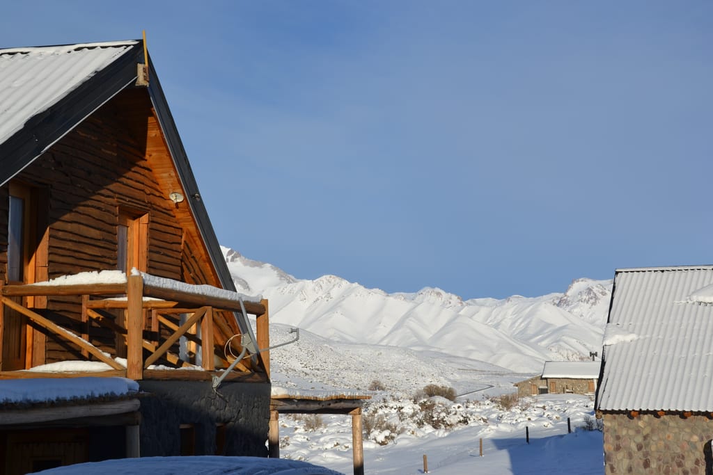 Cabaña con vista a la cordillera nevada en invierno.