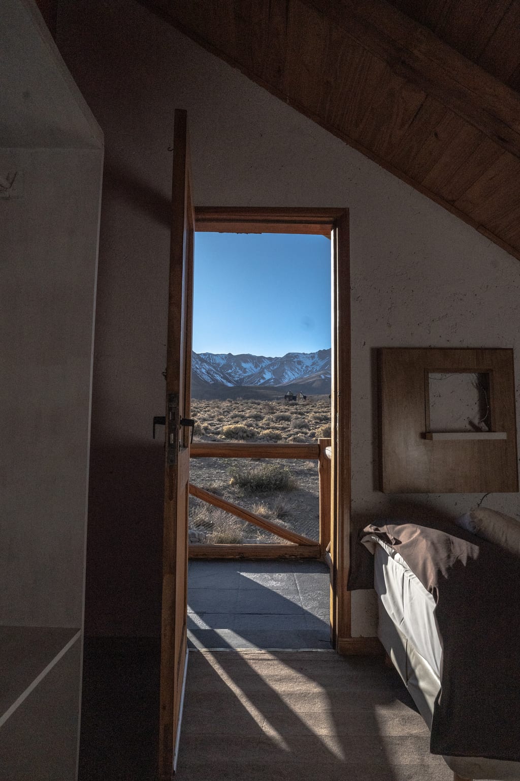 Puerta abierta de la cabaña con vista al paisaje cordillerano.